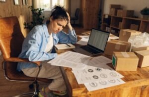 Stressed DTC founder looking at packaging quotes and certification documents, realizing the wrong choice is costing extra money